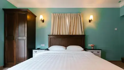a bedroom with a large bed with a wooden headboard at The Tudor in Ipoh