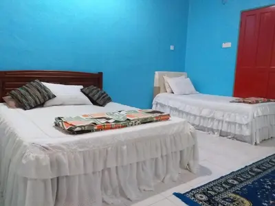 two beds in a room with blue walls at AsSalam Homestay in Seri Iskandar