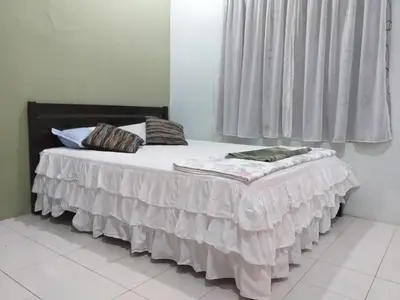 a bed in a room with a white blanket on it at AsSalam Homestay in Seri Iskandar