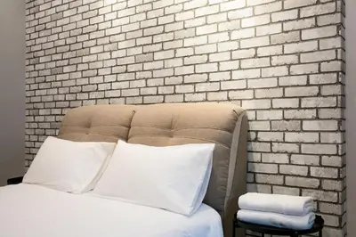 a bed with white pillows in front of a brick wall at Canning 33 in Ipoh
