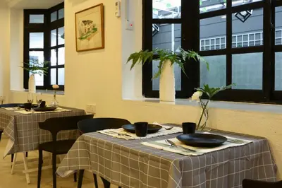 a dining room with two tables and chairs and windows at G Beach Front Villa in Batu Ferringhi