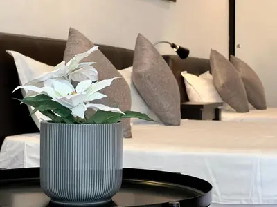 a vase with flowers on a table in front of a bed at G Beach Front Villa in Batu Ferringhi