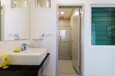 a bathroom with a white sink and a mirror at Straits Garden Suites, Georgetown in George Town
