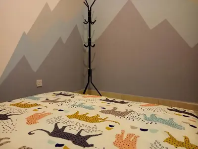 a bed with a quilt on it with mountains on the wall at ICOLOR HOME & STAY CH2 in Tanah Rata