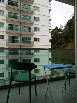 a table and a chair on a balcony with a building at ICOLOR HOME & STAY CH3 in Tanah Rata