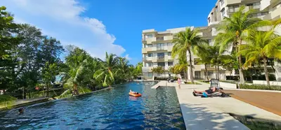 a pool at a resort with people swimming in it at By The Sea Beach Luxury Resort - Batu Ferringhi in Batu Ferringhi