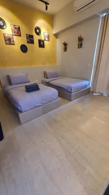 two beds in a room with yellow walls at By The Sea Beach Luxury Resort - Batu Ferringhi in Batu Ferringhi