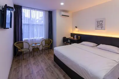 a hotel room with a bed and a table and chairs at Tambun Warm Hotel in Ipoh