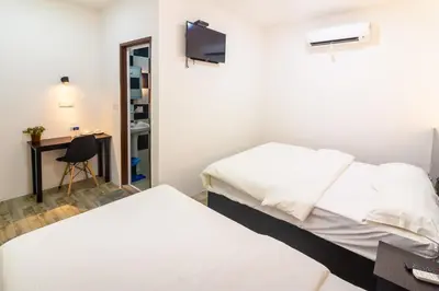 a bedroom with two beds and a desk and a tv at Tambun Warm Hotel in Ipoh