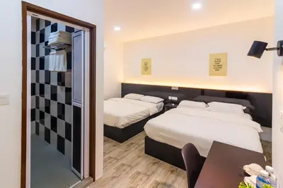 two beds in a room with a desk and a mirror at Tambun Warm Hotel in Ipoh