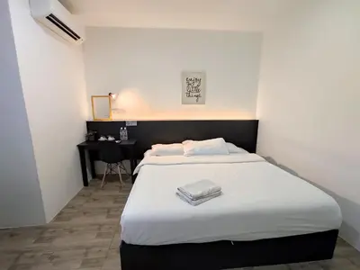 a bedroom with a bed and a desk in it at Tambun Warm Hotel in Ipoh
