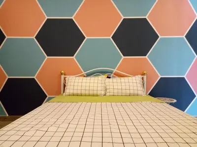 a bed in a room with a hexagonal wall at ICOLOR HOME & STAY CH5 in Tanah Rata