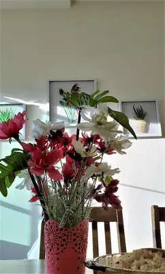 a red vase filled with flowers on a table at Teaz Apartment @ Iris House Resort in Cameron Highlands