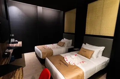 a hotel room with two beds and a red chair at Artworks Hotel Ipoh in Ipoh