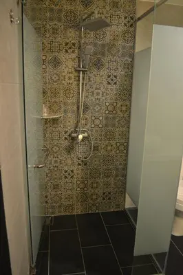 a bathroom with a shower with a tiled wall at Artworks Hotel Ipoh in Ipoh