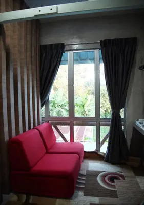 a red couch in front of a large window at Rick Resort Teluk Intan in Teluk Intan