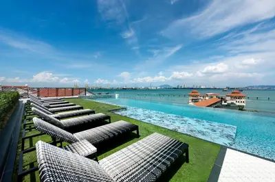 a swimming pool with lounge chairs and the water at The Prestige Hotel Penang, a Member of Design Hotels in George Town