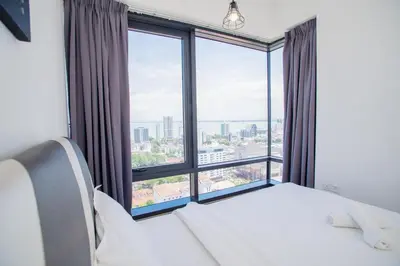 a bedroom with a large window and a bed with white sheets at Tropicana 218 MACALISTER in George Town