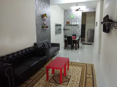 a living room with a black couch and a red stool at Zah’ra Homestay in Kuala Lipis