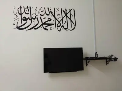 a tv in a white room with a wall with a sign at Zah’ra Homestay in Kuala Lipis