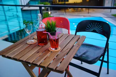 a wooden table with two glasses and a bottle at Sarang by the brook in Kuala Kubu Baharu
