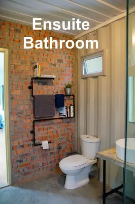 a bathroom with a toilet and a brick wall at Sarang by the brook in Kuala Kubu Baharu