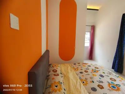 a bedroom with a bed with an orange wall at CLASSIC ENGLISH @ CH in Tanah Rata