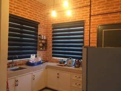 a kitchen with white cabinets and a brick wall at CLASSIC ENGLISH @ CH in Tanah Rata