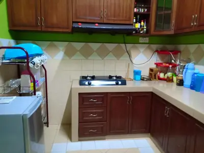 a kitchen with wooden cabinets and a stove top oven at Muslim Dinaim Homestay in Tanjung Malim