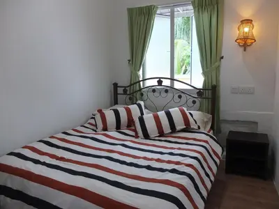 a bed with a striped blanket and a window at Muntri House by Virtue Hospitality in George Town