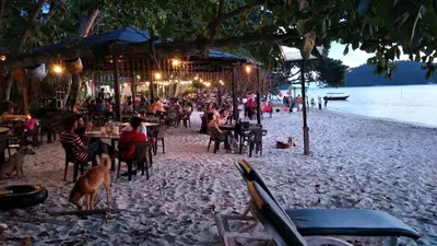 a group of people sitting at tables on a beach at 2sty Villa - Walking Distance To The Beach in Pangkor