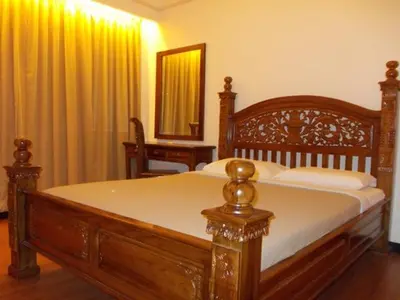 a wooden bed in a bedroom with a mirror and curtains at Bali Style Apartment @ Imperial Court in Cameron Highlands