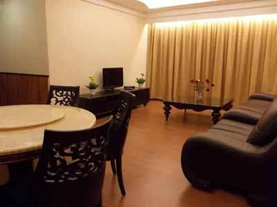 a living room with a table and chairs and a couch at Bali Style Apartment @ Imperial Court in Cameron Highlands