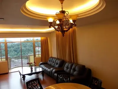 a living room with a leather couch and a table at Bali Style Apartment @ Imperial Court in Cameron Highlands