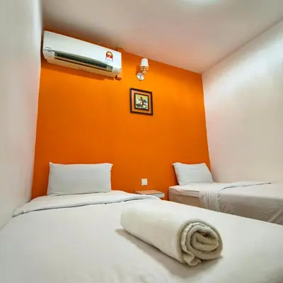two beds in a room with an orange wall at Nice Inn in George Town