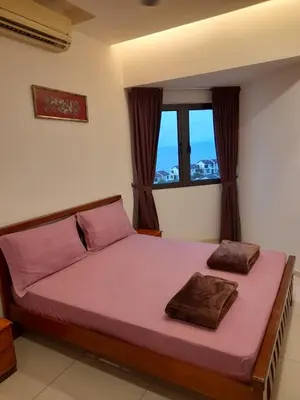 a bedroom with a bed with pink sheets and a window at Susie's VIP Resort Seaview Suite at Sri Sayang in Batu Ferringhi
