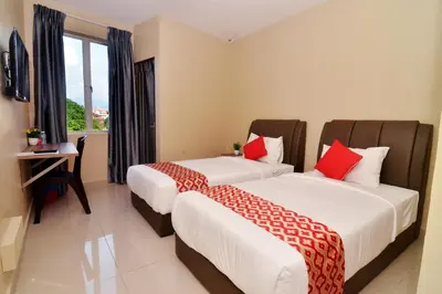 two beds in a room with a desk and a window at Hotel Raub Agro in Raub