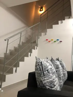 a staircase in a living room with a black couch at De Little Cabin - 7mins to Sunway Iost World of Tambun in Ipoh
