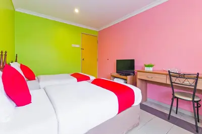 a bedroom with two beds and a desk and a television at Hotel O Comfort in Ipoh