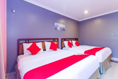 a bedroom with two beds with red and white pillows at Hotel O Comfort in Ipoh
