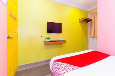 a yellow room with a bed and a tv at Hotel O Comfort in Ipoh