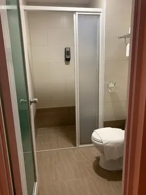 a bathroom with a toilet and a glass shower at Mii Smile Hotel Penang in George Town