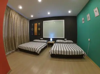 two beds in a room with green walls and a screen at Selamat Datang @ 118 Island Plaza Superior Suite in Tanjong Tokong