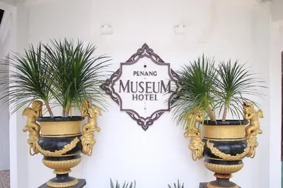 a sign on a wall with two plants in vases at Museum Hotel in George Town