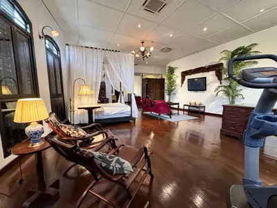 a large living room with chairs and a bed at Museum Hotel in George Town