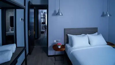a bedroom with a bed and a table with a flower on it at Urban H Hotel in George Town
