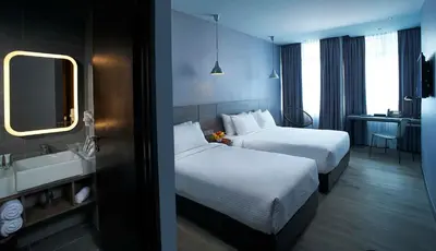 a hotel room with two beds and a sink at Urban H Hotel in George Town