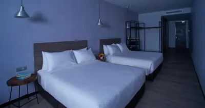 two beds in a hotel room with white sheets at Urban H Hotel in George Town