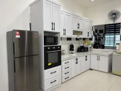 a kitchen with white cabinets and a stainless steel refrigerator at Homestay Samsul Sungkai in Sungkai