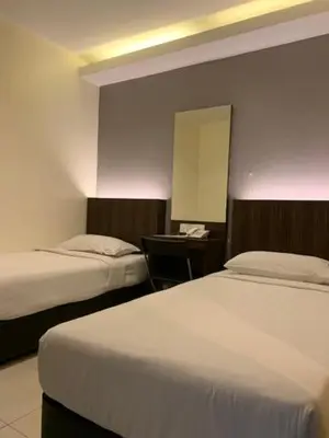 a hotel room with two beds and a mirror at The Regency Garden Hotel in Ipoh